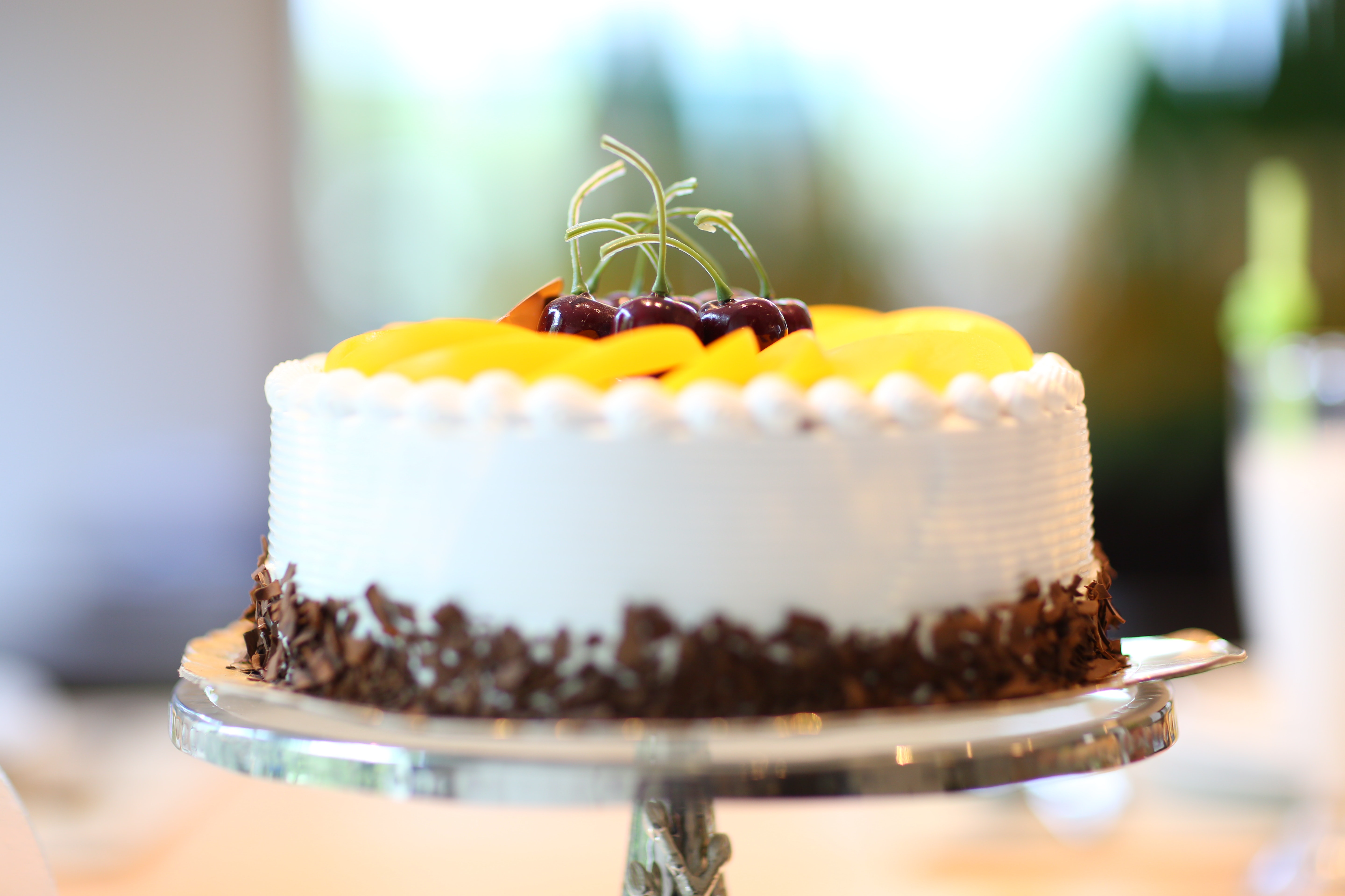 A cake with withe and yellow icing and some cherries on top
